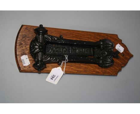 An Edwardian cast iron door knocker/letterbox, with bat detail, mounted on an oak plinth, 30cm