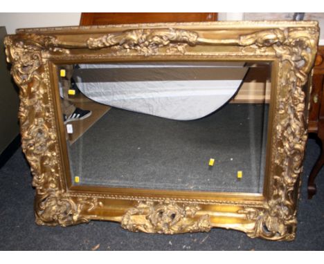 A large gilt composite wall mirror, the pierced frame moulded with acanthus scrolls and flowers around a bevelled rectangular