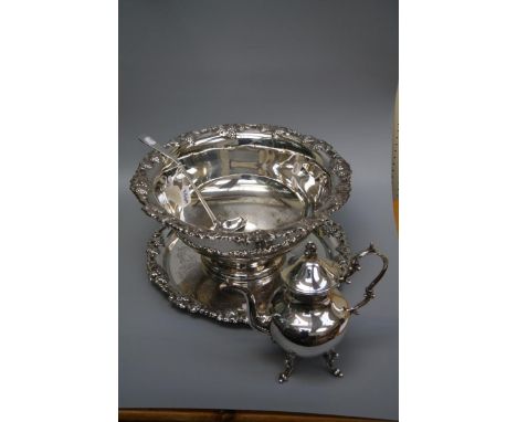 A large Edwardian silver plated punch bowl with fruiting vine cast rim together with ladle, a similar circular tray and an EP