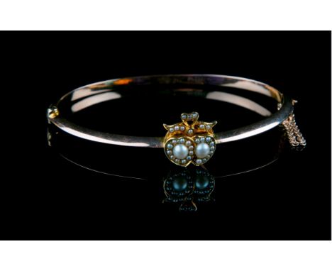 A Victorian 15ct gold and split pearl double heart bangle, the overlapped hearts set with a central split pearl and seed pear