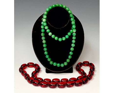 A string of green jade effect beads, approx. 80cm long; a string of faux amber beads, approx. 80cm long (2) 