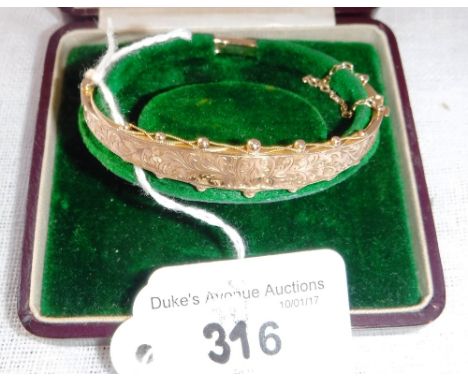 AN EDWARDIAN 9CT YELLOW GOLD BANGLE with engraved front section in a fitted presentation case