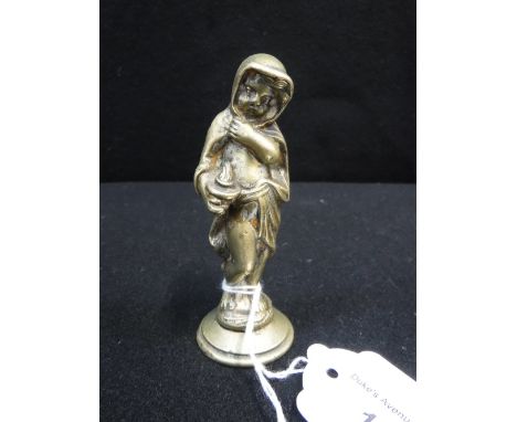 AN EARLY BRASS CAR MASCOT in the form of a cloaked figure holding a lamp, 4" high