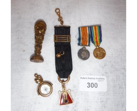 AN UNMARKED YELLOW METAL AND CORNELIAN ART DECO STYLE PENDANT suspended from a black silk metal mounted fob, a compass fob, a