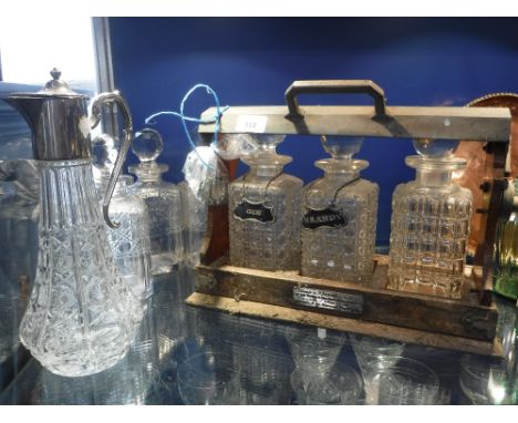 A THREE BOTTLE TANTALUS, three further, decanters, plated decanter labels and a claret jug