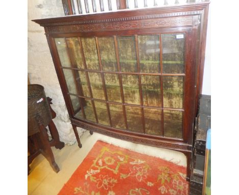 An Edwardian mahogany display cabinet with dentil and blind fretwork cornice, the glazed and barred front panel flanked by do