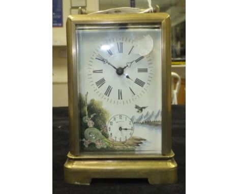 A brass cased carriage clock with enamelled dial decorated with lake landscape with bird and nest of eggs