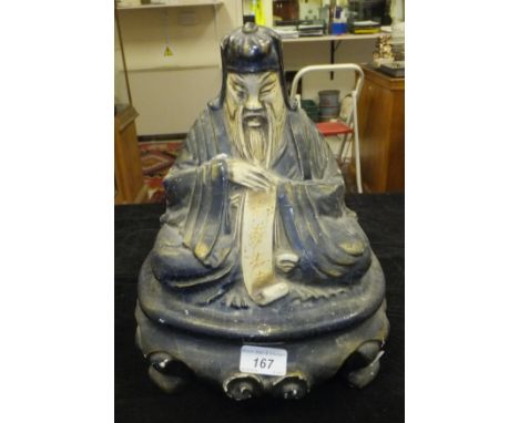A 1920's lacquered papier maché speaker case in the form of a seated Taoist scholar, inscribed to underside "Regd Design Andi