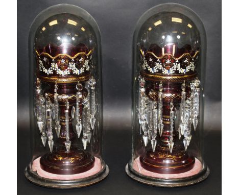 A pair of Victorian ruby glass and floral enamelled and gilt decorated table lustres with glass domes on ebonised plinth base