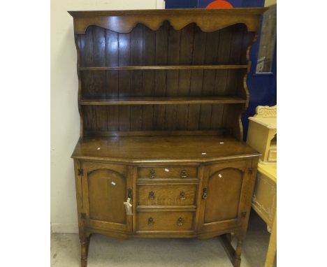 A mid 20th Century oak dresser, the two shelf boarded plate rack above a base of three drawers flanked by two cupboard doors