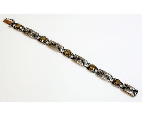 An and Arts and Crafts sterling silver smokey quartz bracelet, by Liberty, with a series of circular mixed cut smokey quartz,