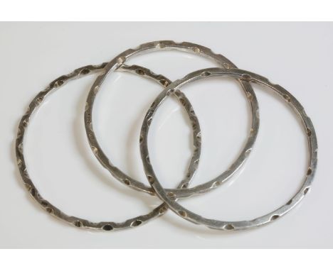 A set of three sterling silver slave bangles, c.1970, by R G Hounslow, each flat section bangle with notched decoration to al