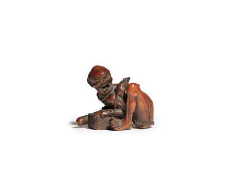 A JAPANESE WOOD NETSUKE OF A THWARTED RAT CATCHER MEIJI PERIOD, 19TH CENTURY The emaciated man kneeling down, turning his hea
