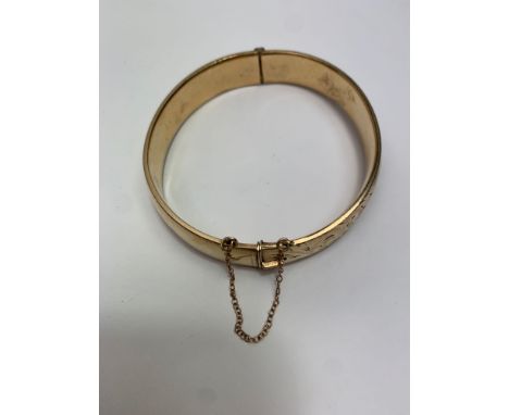 A gilt metal hinged bangle, with half engraved decoration, inner diameter 5.8 cm