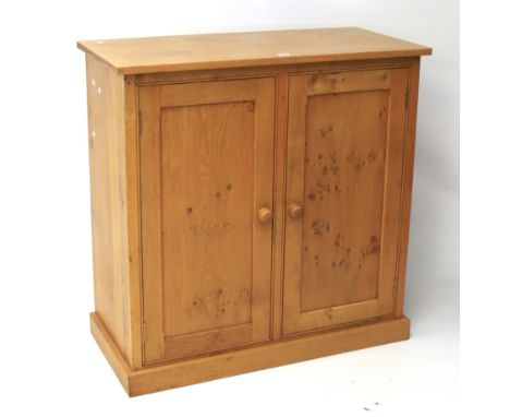 A contemporary burr oak cupboard. The two panelled doors with turned handles opening to reveal a single adjustable shelf, rai