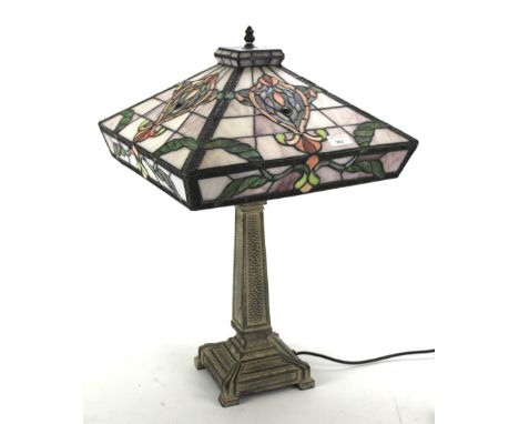 A Tiffany style coloured leaded glass table lamp. The shade of square form, with a cast metal column base, fitted for electri