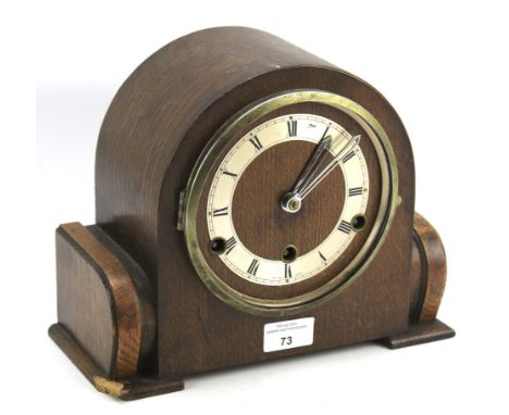 A 20th century mantel clock. The silvered dial with Roman numerals, the oak domed cased with carved ends, the movement no 539
