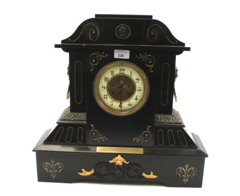 A Victorian mantel clock. The enamel dial with Roman numerals, the slate case with engraved and gilt details, a plaque to the