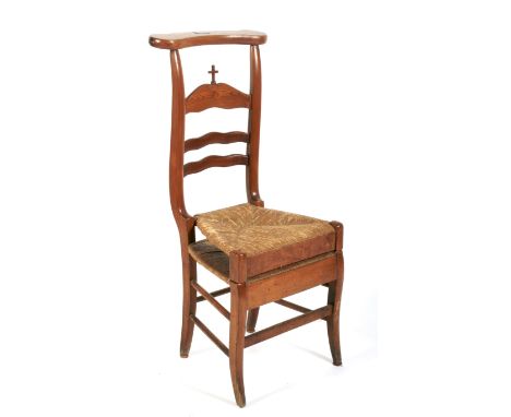 A late 19th century French fruitwood and pine prie-dieu. With shaped rest above ladder back and cross, with hinged rush seat 