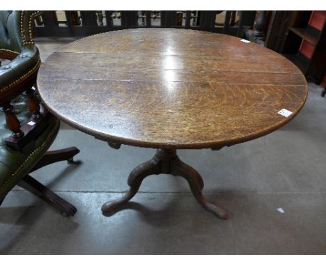 A George III oak circular tilt top table with baluster turned column on tripod supports