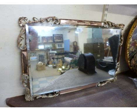 An Art Deco mirror with peach glass and scroll border