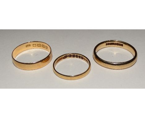 Two 18ct gold wedding bands, ring sizes L and R, 18 stamped to underside, 4.1g, together with a 9ct gold wedding band, stampe