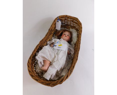 A Huebach Koppelsdorf bisque head doll, no 267.1, 37cm high., together with a wicker doll's cot, 47cm wide. (2)