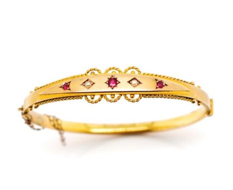 Victorian 9ct yellow gold bangle set with seed pearls and garnets. Marked 9ct to tang, with swivel hinge and safety chain. Ap