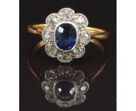 An 18ct gold ring set with an oval cushion cut sapphire of approximately 0.5ct surrounded by diamonds in a platinum setting, 