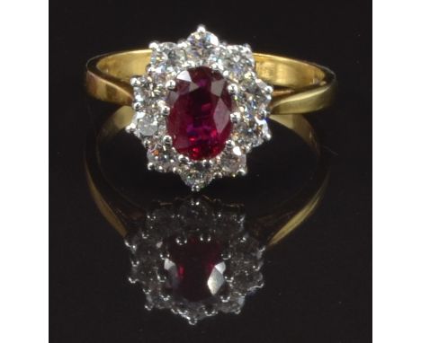 An 18ct gold ring set with an oval cut ruby of approximately 0.9ct surrounded by ten round cut diamonds, size P, 4g&nbsp;