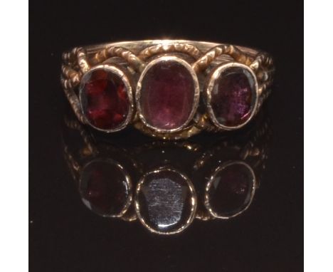 An early Victorian rose gold ring set with three oval cut foiled garnets, size N, 2.3g