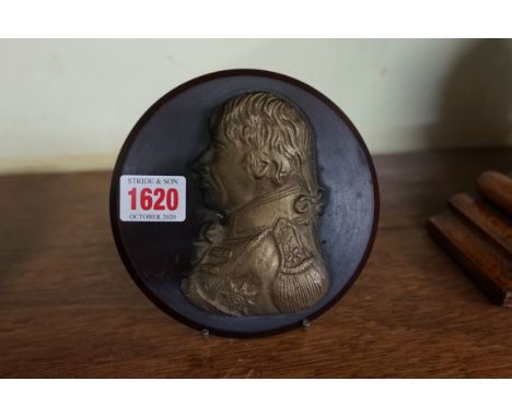A gilt metal portrait relief plaque of Horatio Nelson, 11cm high, on composition circular plaque.&nbsp; 