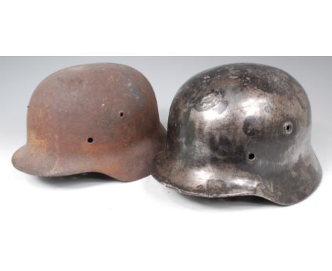 A German model 1935 steel helmet, lacking decals and interior, together with three other battlefield find German helmets. (al