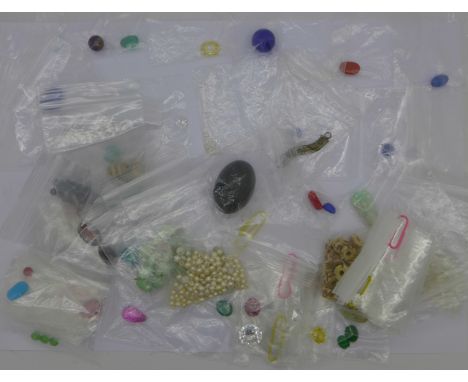 A collection of unmounted semi-preciuos stones and beads including a ruby, a carved jade pendant, cabochon and faceted