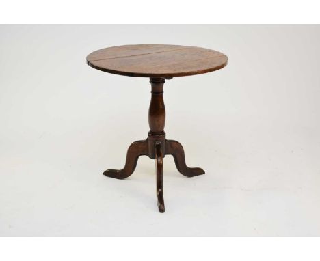 An 18th century Welsh oak tilt-top tripod table, the plain circular top on a baluster stem with three scroll feet, 70cm wide 