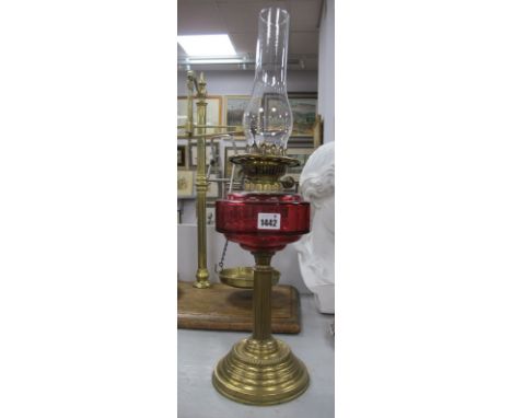 An Early XX Century Iron Weighted Brass Oil Lamp, with cranberry glass well.