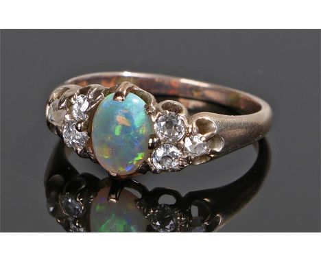 18 carat gold opal and diamond ring, the central oval opal flanked by three diamonds to each shoulder, ring size O