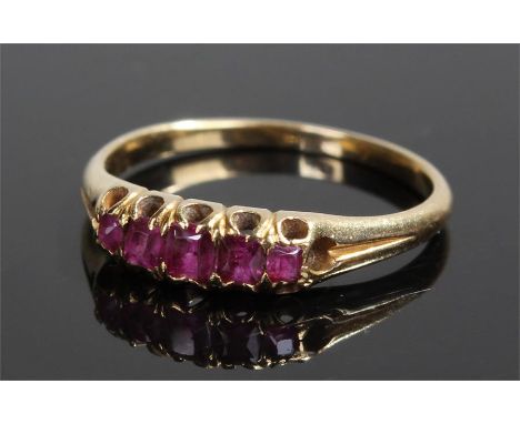 Yellow metal ruby set ring, with a row of five rubies to the head, ring size M