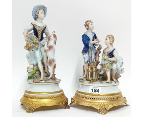 Two German Sitzendorf style figurines, depicting a girl and boy and girl and dog, on gilt stands. (2)