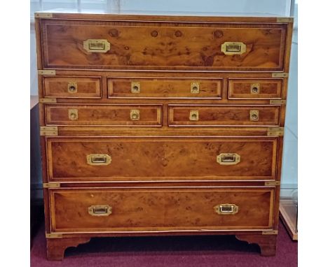 A modern yew and brass mounted campaign chest of drawers, with decorative veneered front and recessed handles, on bracket fee