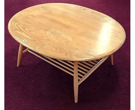 An Ercol beech oval coffee table, with turned wood magazine rack, height 44cm, length 99cm