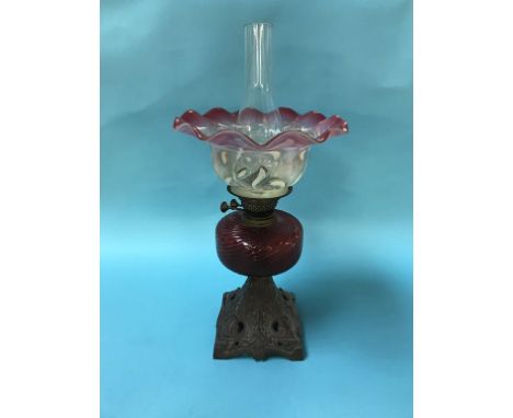 An oil lamp with cranberry and opaque crimped shade and cranberry reservoir
