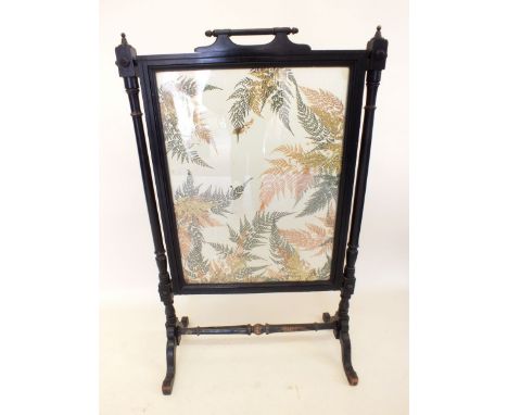 A Victorian ebonised fire screen with glass panel inset dried flowers and ferns