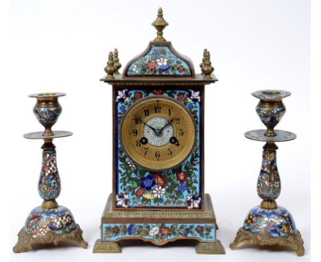A late 19th century brass clock garniture, with champlevé enamel floral decoration, the clock having a 6.5 cm diameter dial w