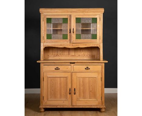 An early 20th century pine side cabinet or dresser with stained glass doors opening to reveal a fixed shelf above two short a