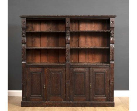 A late 19th century carved oak bookcase with open shelves above panelled doors below, all raised on a plinth base, including 