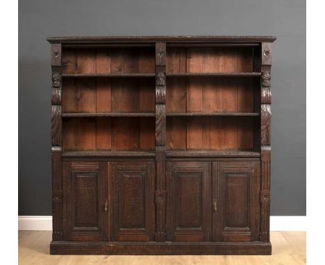 A late 19th century carved oak bookcase with open shelves above panelled doors below, all raised on a plinth base, including 