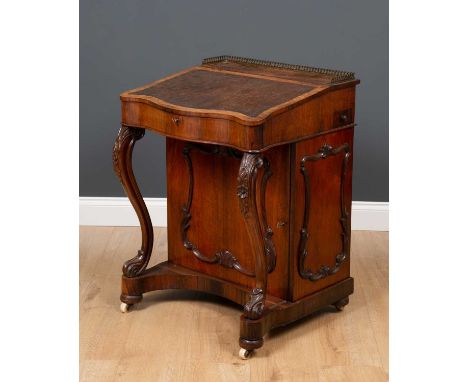 An early Victorian rosewood Davenport desk, the leather inset fall with serpentine front, lifting to reveal two pigeon holes 