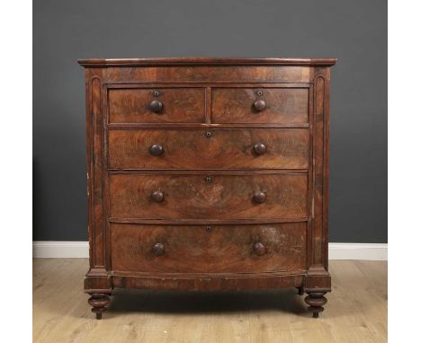 A Victorian mahogany bow fronted chest of two short and three long drawers with turned knob handles and raised on turned feet