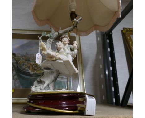Figural lamp base, decorated with children on swing, with pink shade, height 80 cm 